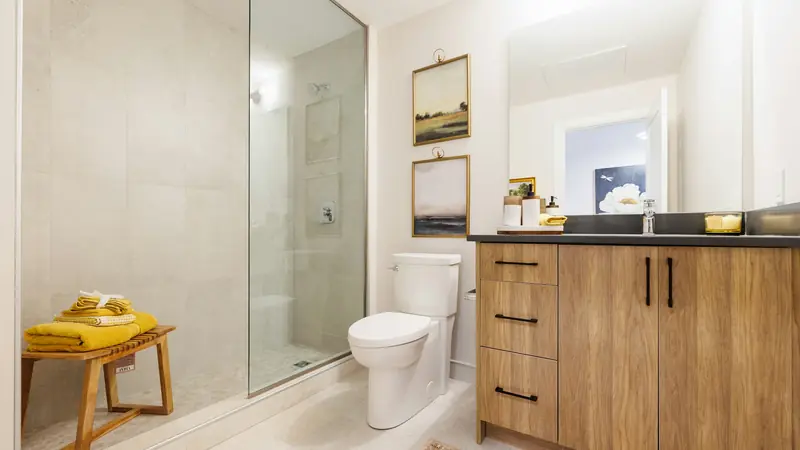 Clean bathroom with a wooden vanity, round mirror and glass shower