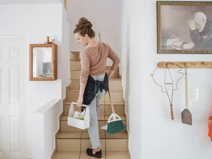 Cleaning caddy and broom on a staircase in a bright home